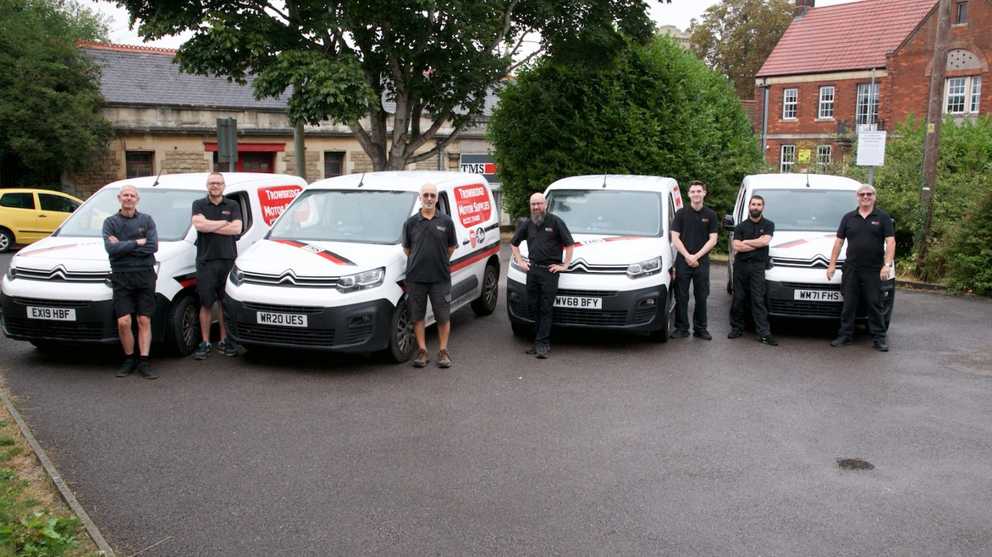 5 TMS staff members stood next to 4 company vehicles